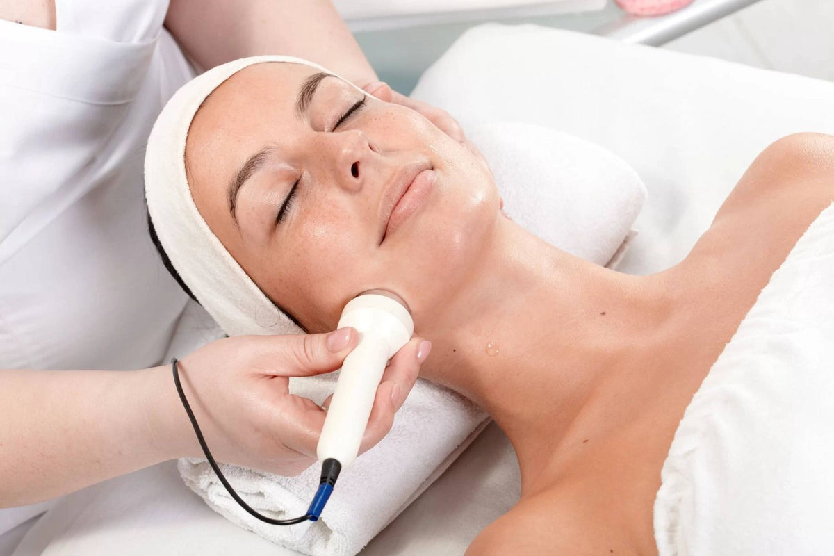 Therapist using a radio frequency handpiece on a client's jaw and neck